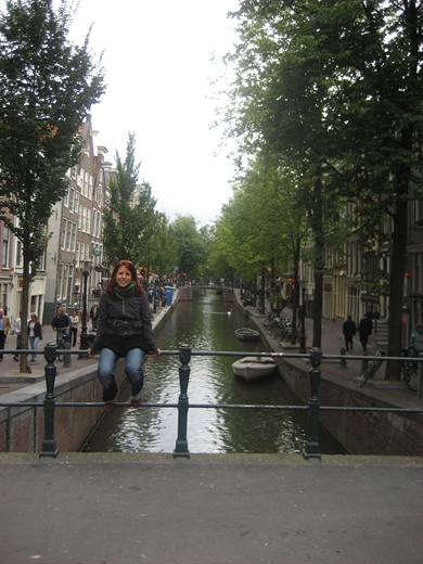 Julia thront auf dem Brückengeländer, unter ihr zieht still die Amsterdamer Gracht