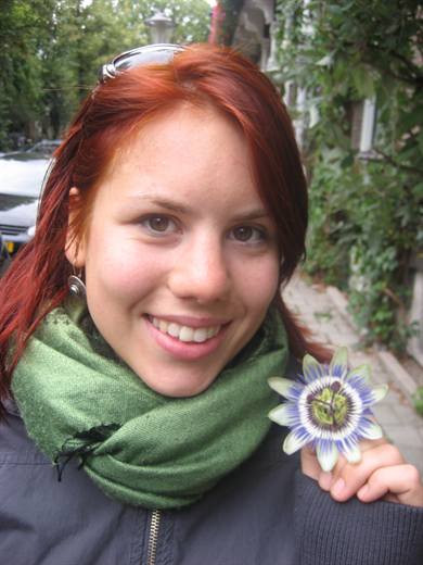 Julia hält eine Passionsblume in die Kamera, der grüne Schal passt wie bestellt