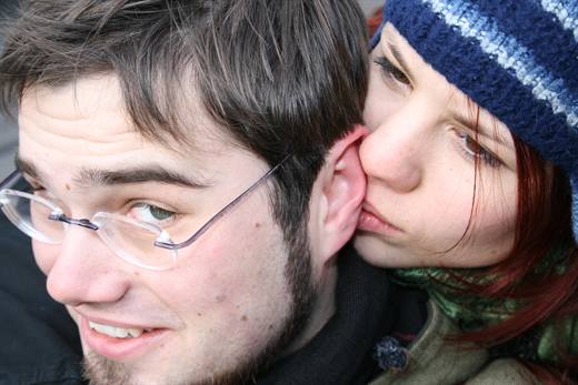 Julia knabbert an Polas Ohr, der grinst, als wäre es das Normalste der Welt