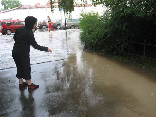 Sommerregen 2009, mit Kapuze und ausgestrecktem Finger wird die Riesenpfütze begutachtet