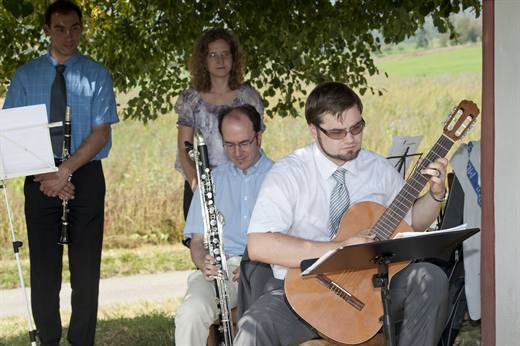 Pola im Einsatz als Festmusiker, konzentriert an der Gitarre im Schatten unter dem Baum