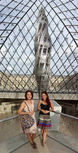 Julia und Begleitung unter der Louvre-Pyramide, dahinter schraubt sich ein Turm in die Höhe