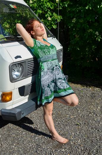 Julia tankt Sonne am alten VW-Bus, barfuss auf dem Kies und ganz im Ferienmodus