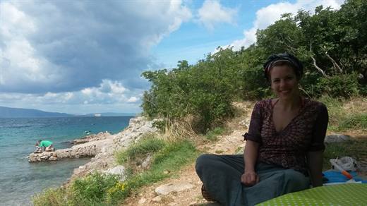 Julia mit Kopftuch am Picknickplatz über der Felsenbucht, das Meer leuchtet türkis