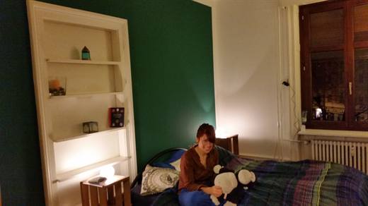 Julia auf dem Bett mit zwei Plüschtieren, die grüne Wand macht das Zimmer gemütlich