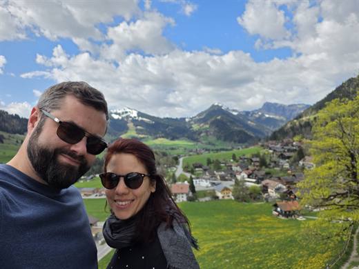 Selfie überm Bergdorf, hinter Julia und Pola noch Schneereste, unten blüht der Löwenzahn